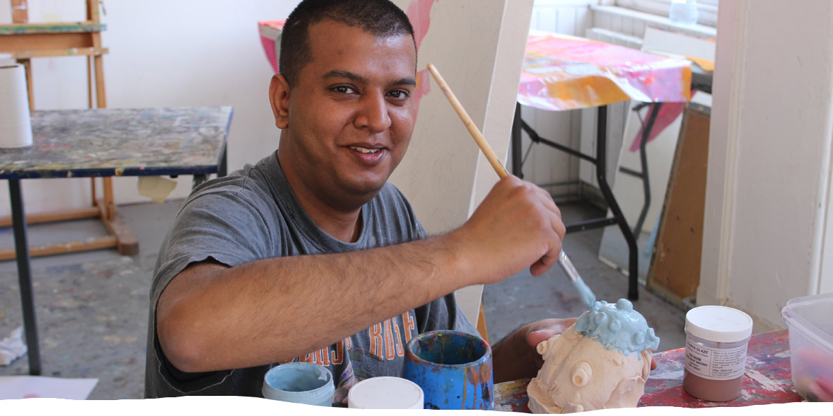 Artist holding paintbrush, and smiling, in the studio