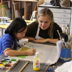 Volunteer Elisa Coffey helps young artist