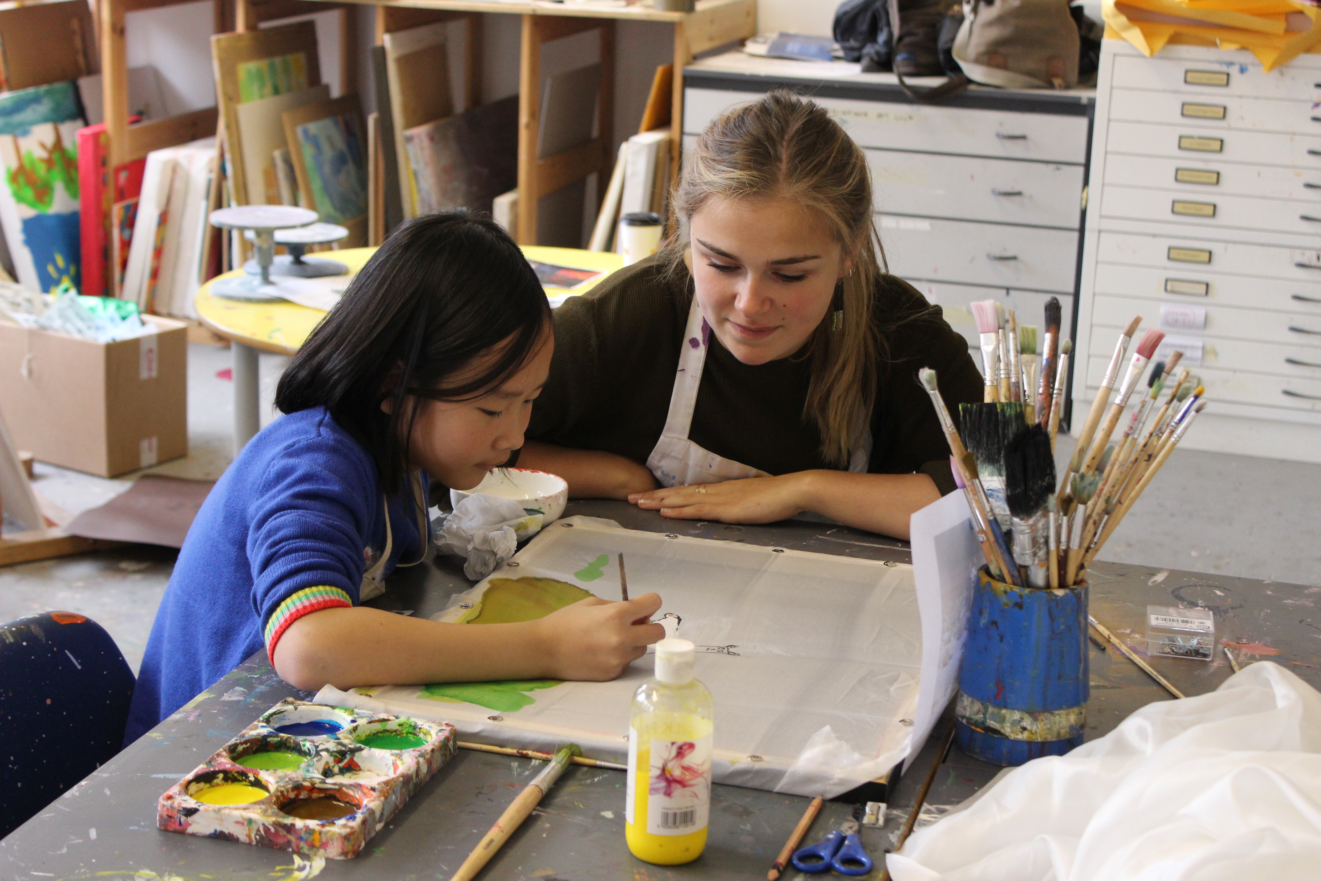 Volunteer Elisa Coffey helps young artist