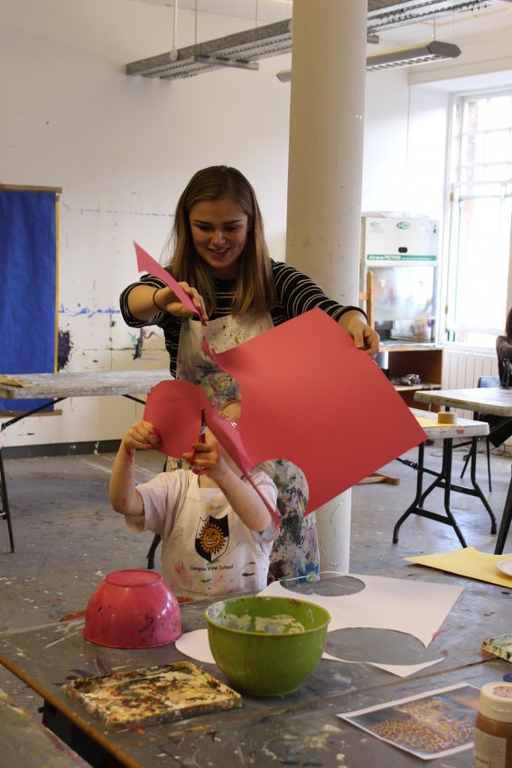 Volunteer Elisa Coffey helps a young artist