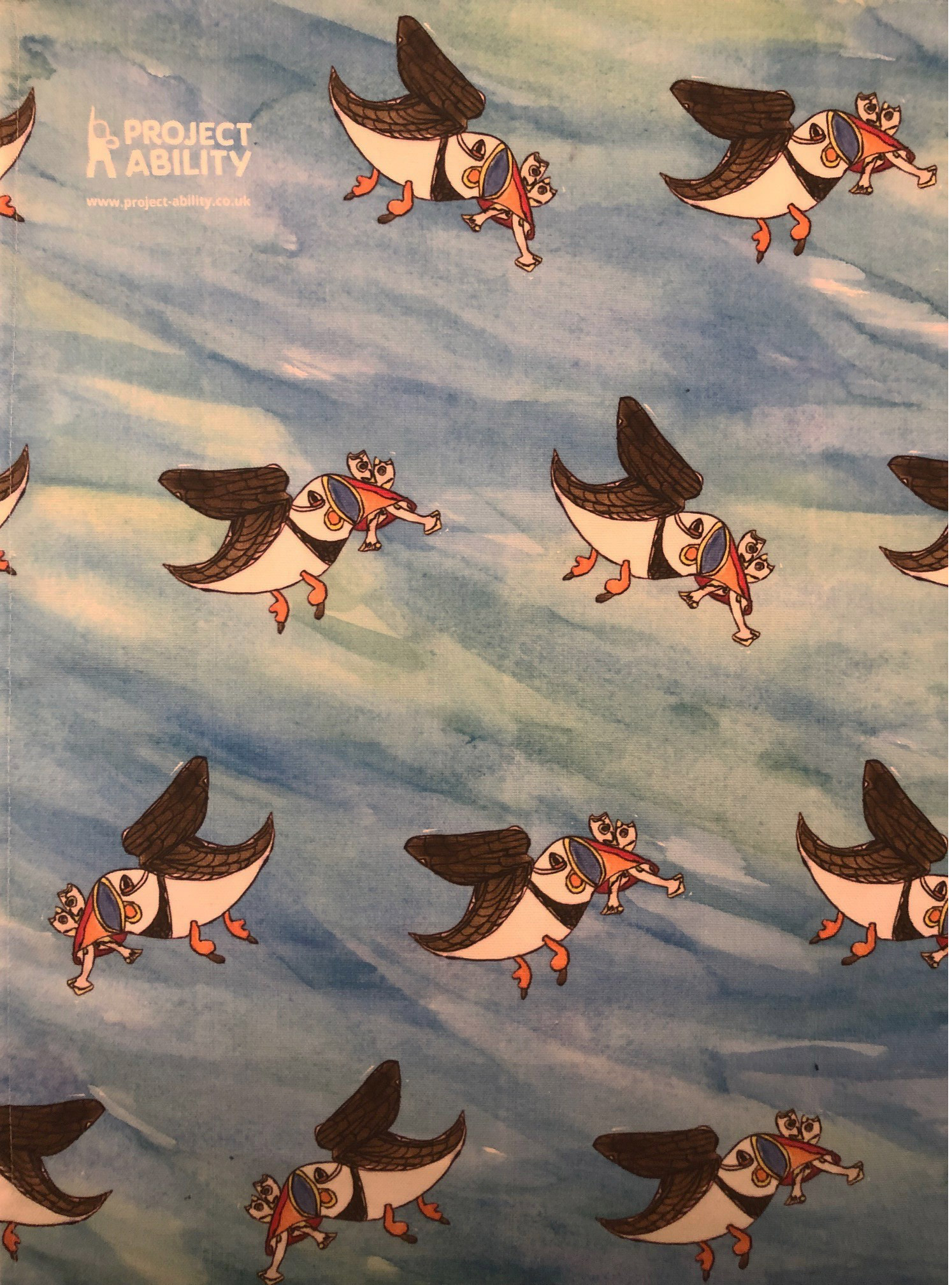 tea towel of blue sky with puffins by Cameron Morgan