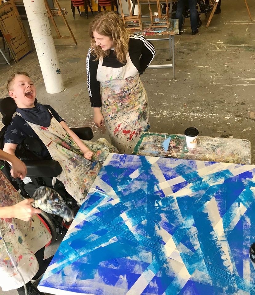 Vivian, a volunteer stading with one of the young participants showing his artwork