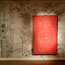 Another gallery wall with one large wooden framed image. You can see the wood grain coming through the red paint covering the background. In the middle of the piece it has 'Is that a rhetorical question?' written in white with a large handrawn circle round it. it is then scribbled at the bottom *silence*