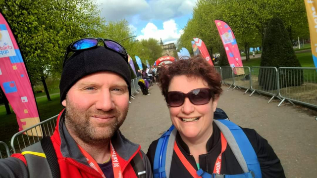 Iain and Vikkie in their Kiltwalk gear, smiling at the camera.