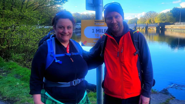 Vikkie and Iain standing in their walking gear by the water.
