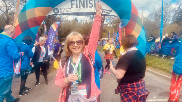 Cathy by the Kiltwalk finish line, her fist up in the air in triumph.