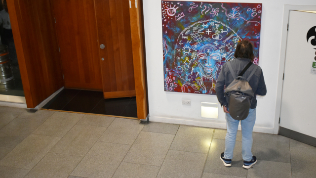 A viewer looks at one of the paintings at the opening event of the exhibition.