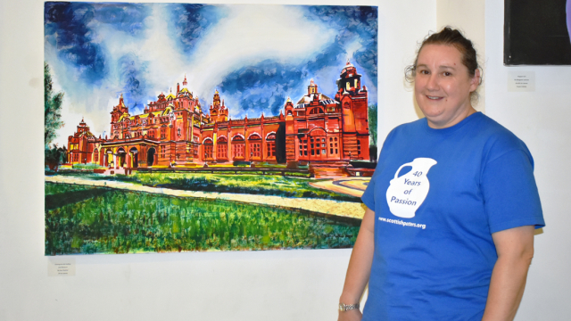 An artist stands in front of their painting of Kelvingrove Art Gallery