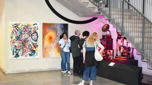 People look at the Sharmanka kinetic sculptures next to the paintings in the exhibition opening event