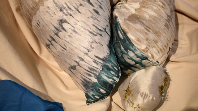 A close up photograph of a three silver squishy artworks nestled together. The colours are cream, gold, silver and metallic teal and there is embroidery growing like moss on the smaller piece.