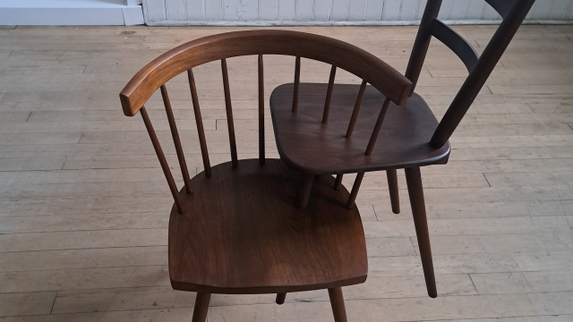 Two connected chairs, making an interesting sculpture, presented in a gallery space.