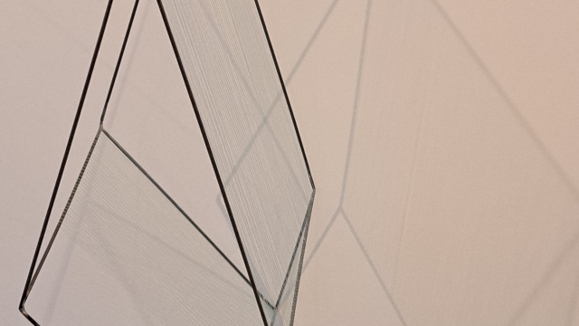 A floating sculpture of sharp corners and a black metal frame. It casts a shadow behind it on the wall.