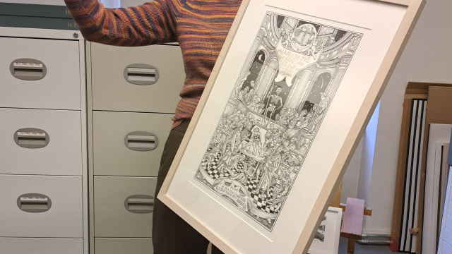 A person holds up a black and white print of a busy scene in which a group of people are witnessing someone dissect a dead body.