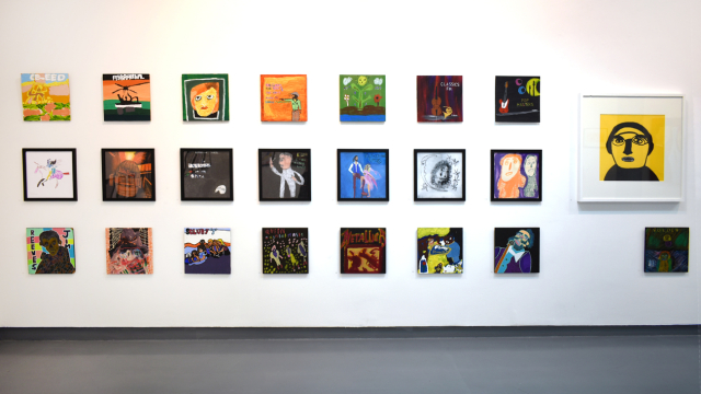 A photograph of the exhibition showing rows of paintings inspired by record covers and one larger portrait of Phil Collins in bold black pen on a yellow background.