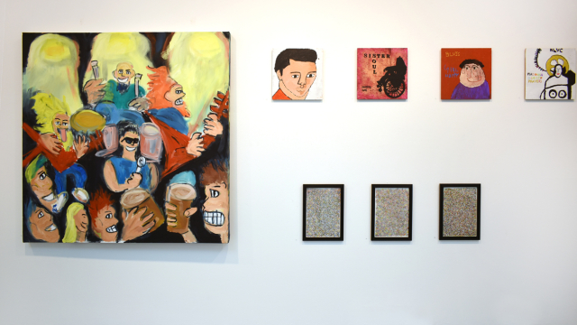 A photograph of the exhibition showing a large painting of a rock concert, a row of paintings inspired by record covers and row of small paintings made up of delicate multicoloured marks.