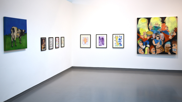 A photograph of the exhibition showing a painting of a cow, portraits of musicians in different media and a large painting of a rock band concert