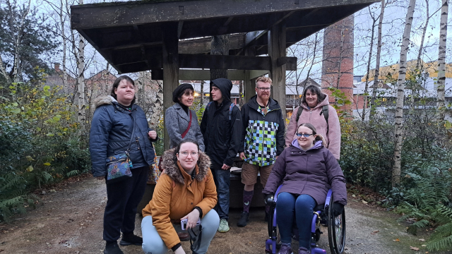 A group of people who are dressed up for the cold and the rain pose for the camera in an outdoor shelter at a garden.