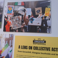 Museum display featuring a protest photo with colorful signs reading “Art Saves Lives” and “Cultural Poverty,” beside a Greater Govanhill collective action panel.